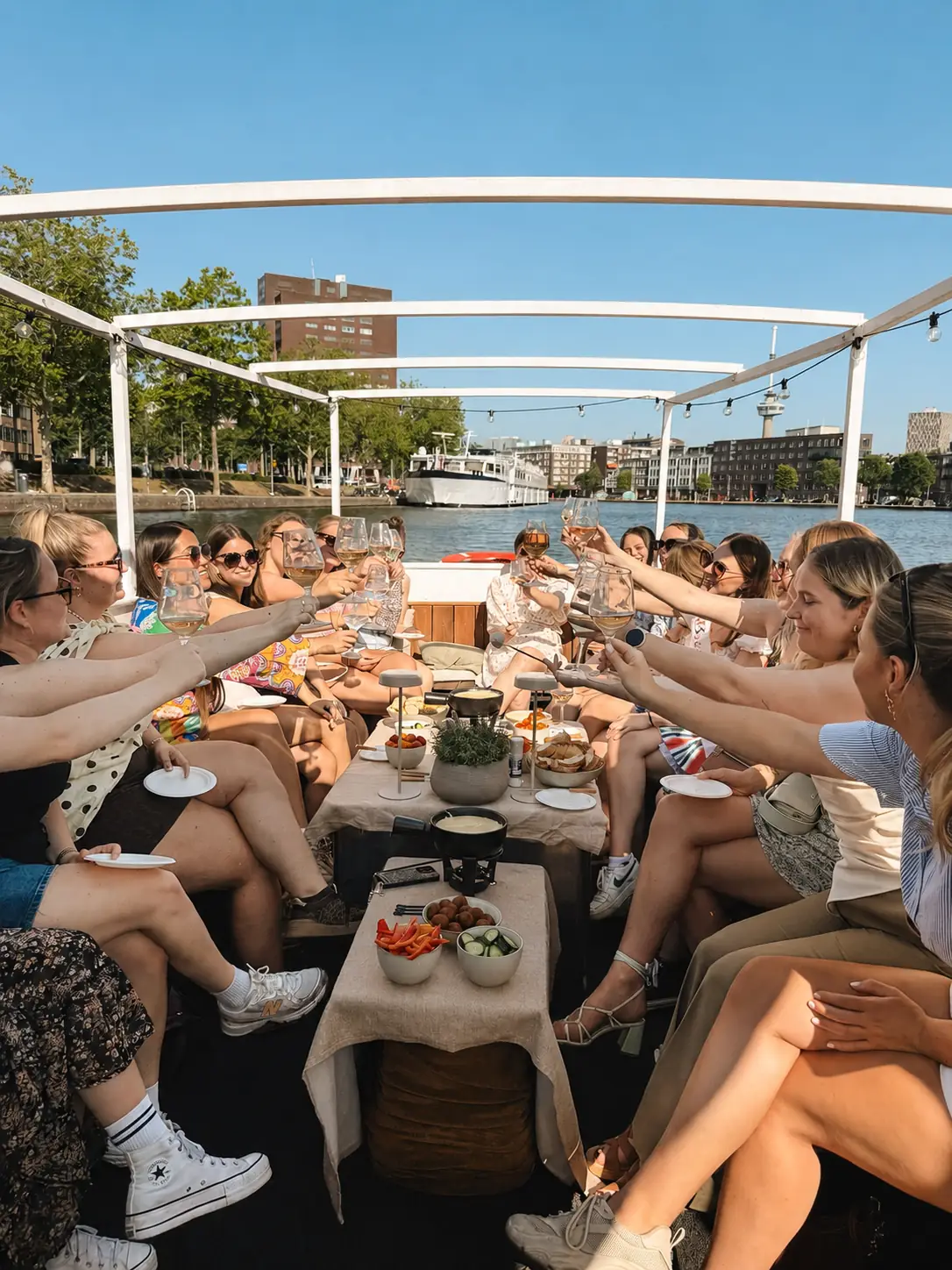 Grote groep geniet van een gezellige rondvaart door Rotterdam met schipper, borrelhapjes en drankjes aan boord.